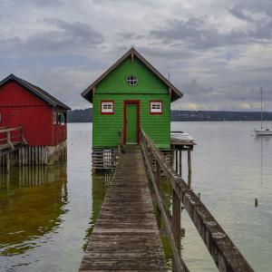 Image of a dock and a green house on the water.